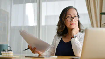 Woman sits at desk and looks at laptop