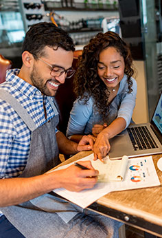 man and woman smiling at a table with a laptop