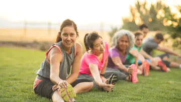 Fitness enthusiasts stretch their hamstrings in the park