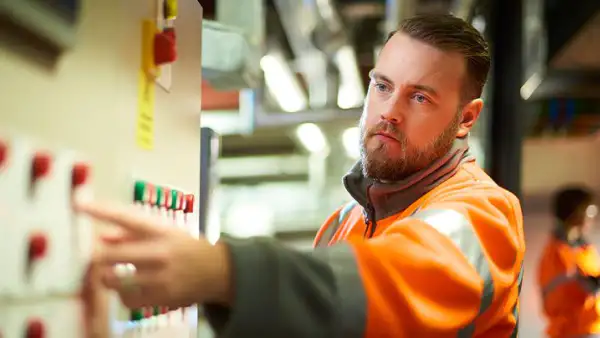 Man pointing at board, heap big important vest