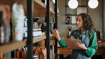 Woman holds clipboard, checks store inventory